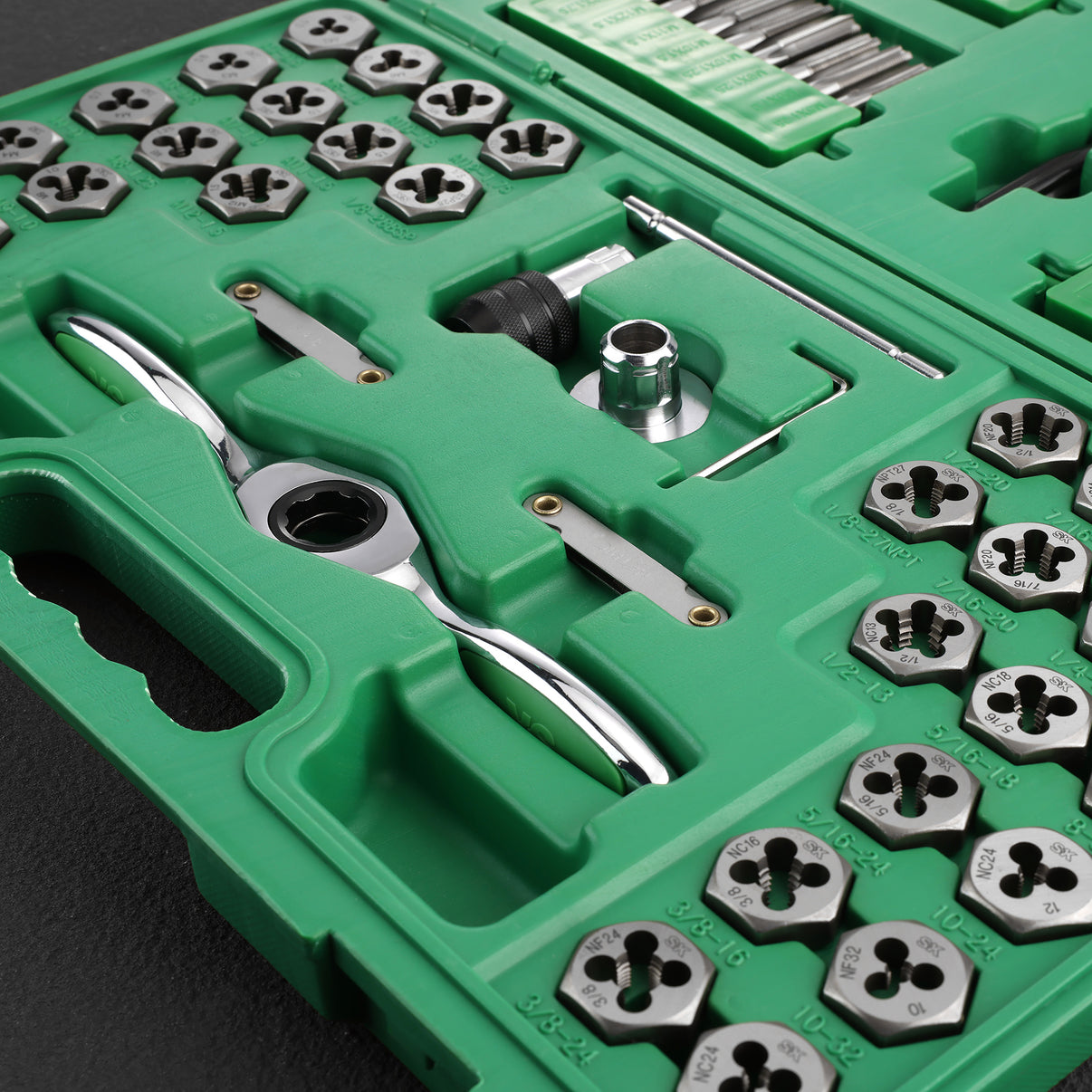 Green tool kit with various metallic tools and components on a dark background